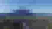 Panorama mit Gemeinde, Feldern und Bergkulisse unter klarem Himmel