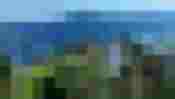 Photovoltaikanlage an einem bewaldeten Berghang mit Seen und Bergen im Hintergrund